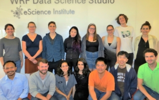 Fifteen of the Data Science for Social Good fellows pose in front of the WRF Data Science Studio sign