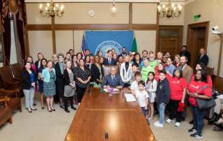 Gov. Inslee signs Engrossed Substitute Senate Bill No. 5600, May 9, 2019. Relating to residential tenant protections. Primary Sponsor: Patty Kuderer. Tim Thomas stands left of the Washington flag.