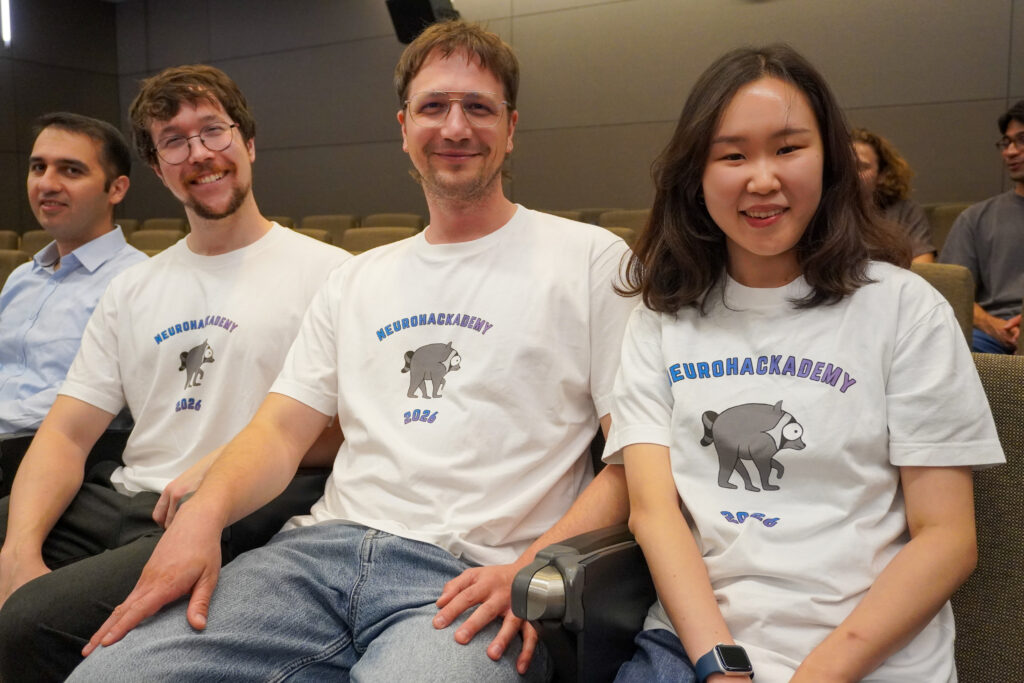NeuroHackademy participants pose with shirts picturing Jimothy the raccoon.